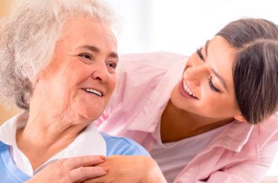 senior woman and caregiver smiling