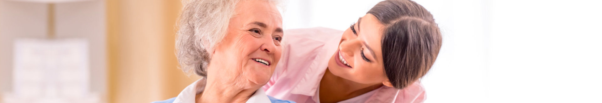 senior woman and caregiver smiling