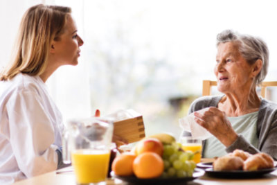 physicians talking to senior woman about nutrition and diet adjustments with healthy foods in the table