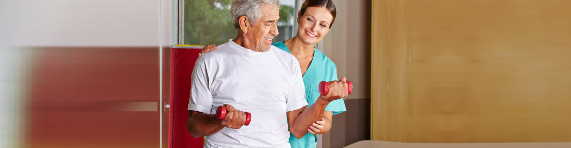 physical therapist assisting a senior man exercising with dumbbells