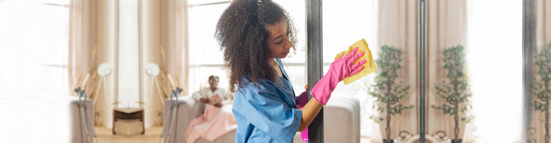 caregiver cleaning the glass door at home of the senior woman