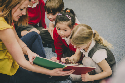 Teacher is sitting in the classroom with her primary school students
