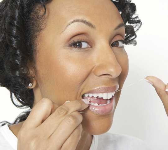 Closeup portrait of an African American woman flossing her teeth