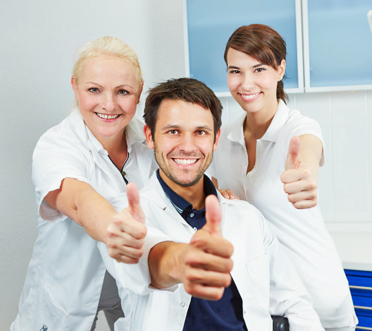 Portrait of smiling dental team with their thumbs up