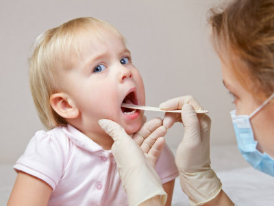 Pediatrician examining little girl's throat