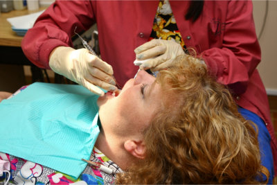 A female women with reddish curly hair lies back in a dental chair