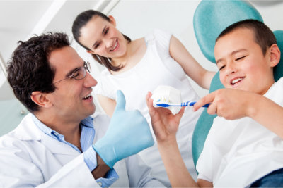 Dentist showing a boy how to brush his teeth