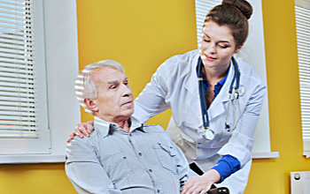 nurse assisting the elder man in a wheelcahir