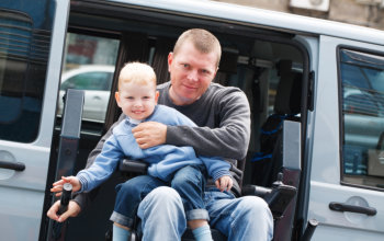 man in wheelchair carrying his son